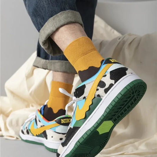 Colorful sneakers with a cow pattern worn with mustard yellow socks on a neutral background