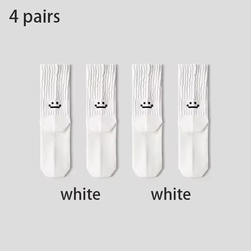 Four pairs of white socks with smiley face designs on a gray background