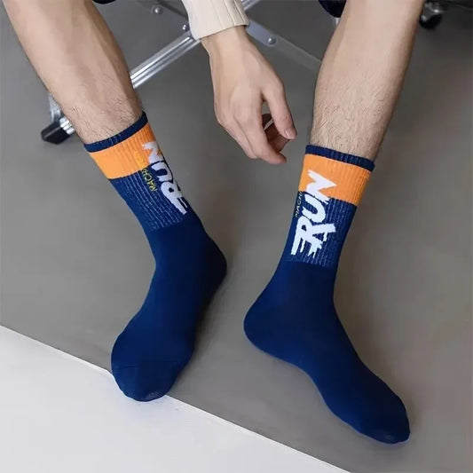 Person wearing blue socks with orange accents and visible branding on a neutral background
