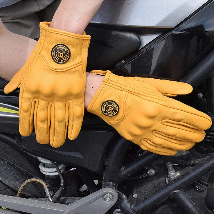 Yellow gloves with a brand logo worn by a person working on a motorcycle, with text 'VENTILATED & BREATHABLE' above.