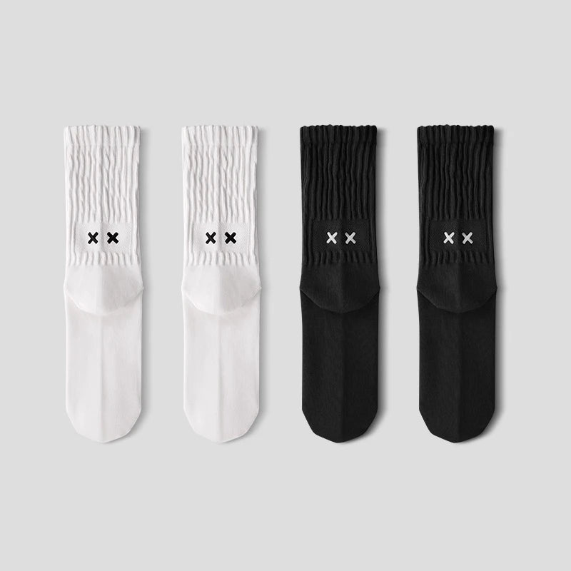 Two pairs of white socks and two pairs of black socks with logo on a light gray background