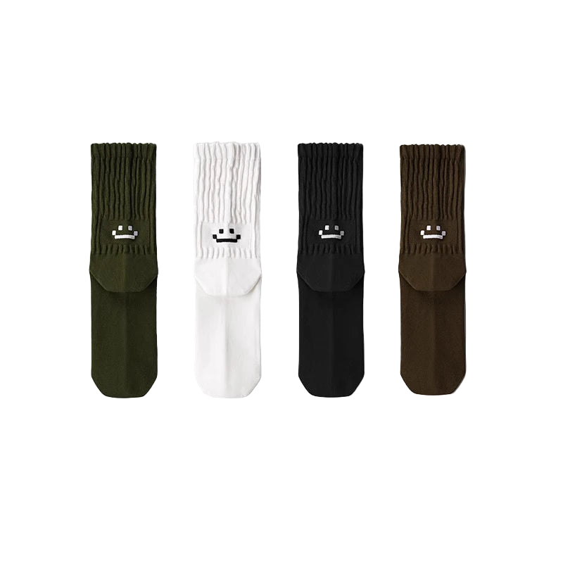 Four pairs of socks in green, white, black, and brown with smiley face designs on a gray background.