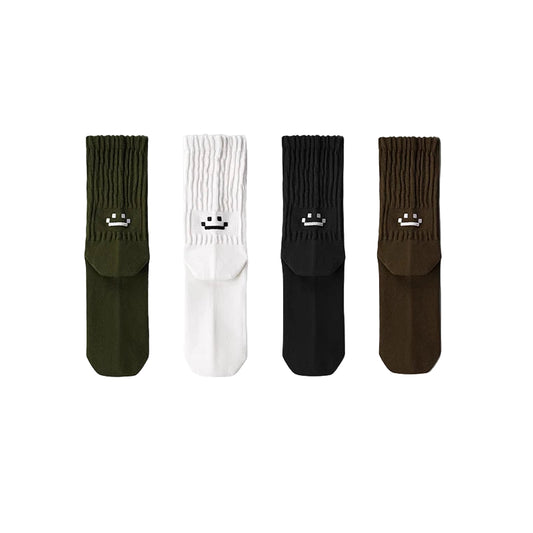 Four pairs of socks in green, white, black, and brown with smiley face designs on a gray background.